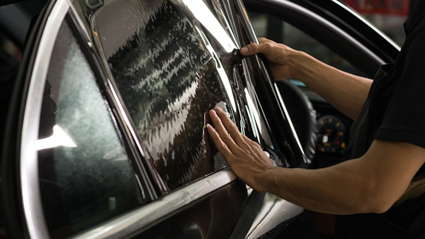 technician applying window tint film to car
